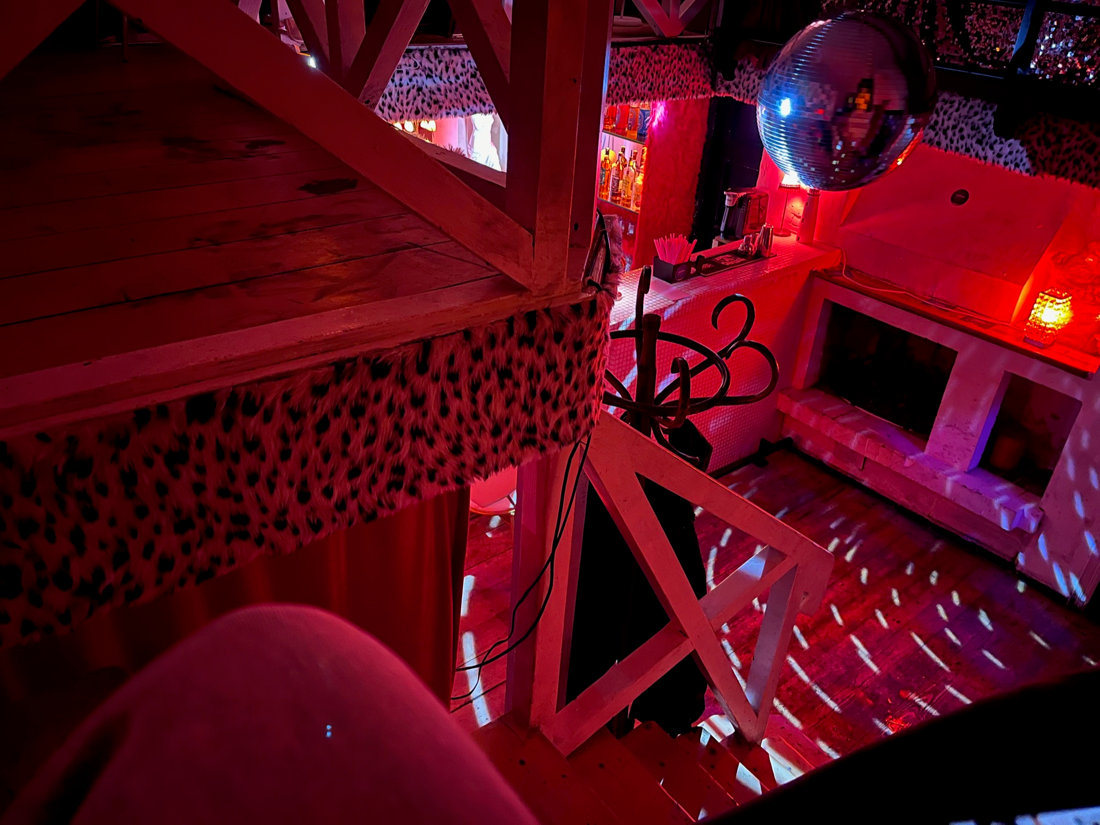 Stair view in a cozy redlight disco ball atmosphere. The stairs are wooden, some planks on the sides are layered with fur imitation.
